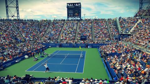 Elevated photo of tennis stadium with large crowd watching a match.