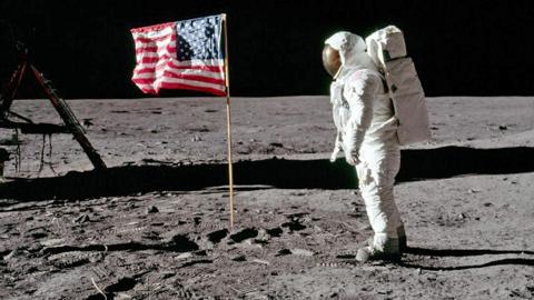 Astronaut on the moon standing near the American flag