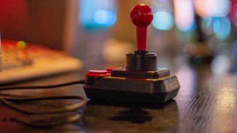 Close up of a video game joystick circa 1980s and the edge of a computer screen and keyboard.